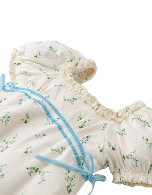 Flatlay front view of the Giselle Dress showcasing its floral pattern, puff sleeves, and ribbon accent.