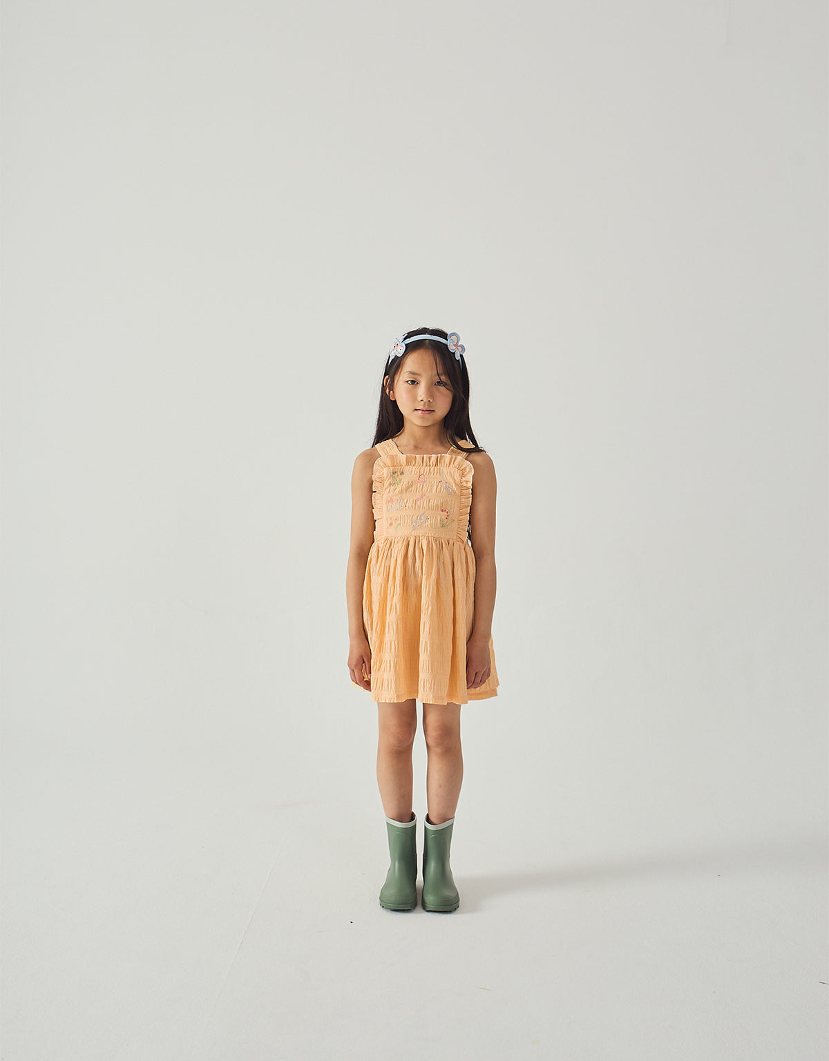 Campaign photo of the Emily Ruffled Apron Dress with Botanical Embroidery for kids from the Spring Summer collection of Filipino kids fashion brand Gingersnaps Philippines, featuring yellow gingham fabric, botanical embroidery, and wide apron straps.