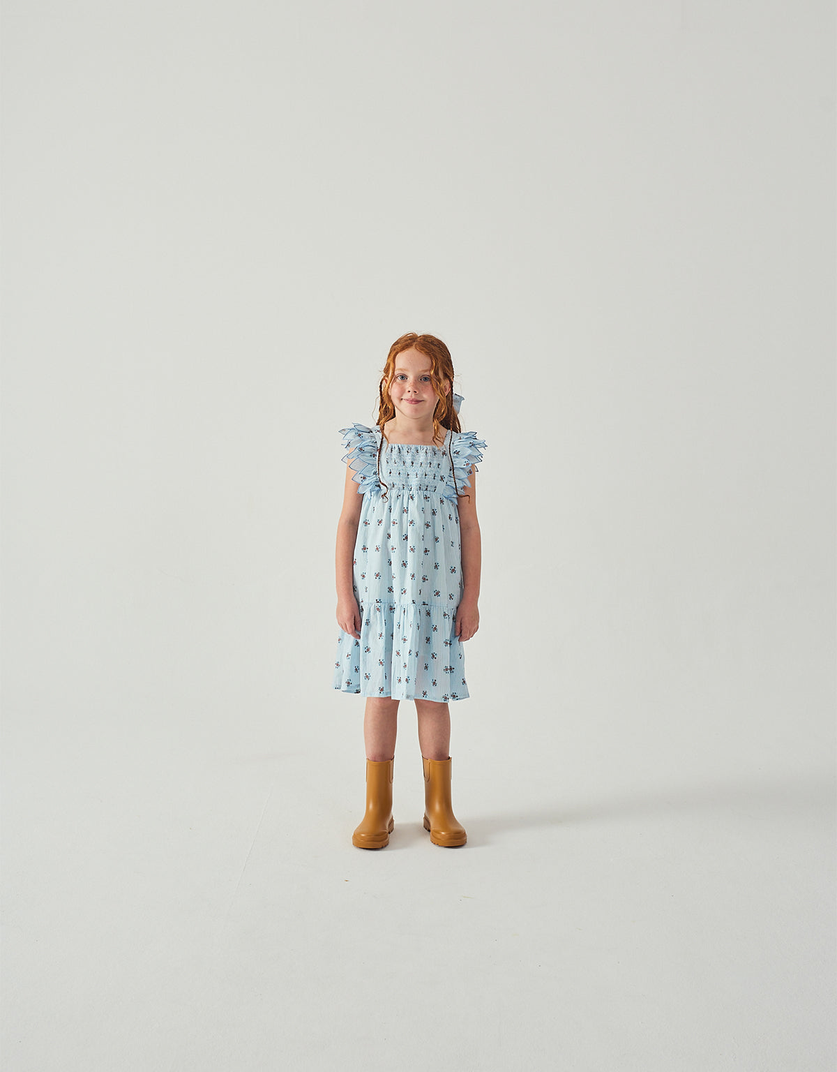Campaign photo of the Chloe Apron Dress with Smocked Bodice & Petal Sleeves for kids from the Spring Summer collection of Filipino kids fashion brand Gingersnaps Philippines, featuring a smocked bodice and fluttering petal sleeves.